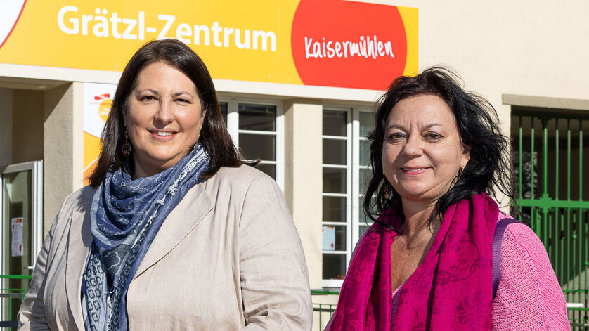 Viezbürgermeisterin Gall steht mit wohnpartner-Bereichsleiterin Claudia Huemer vor einem Gebäude. Über dem Eingangsportal ist der Schriftzug Grätzl-Zentrum Kaisermühlen zu lesen..